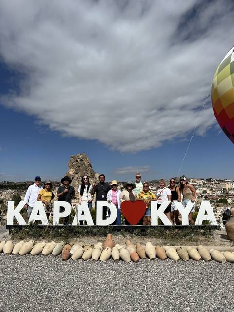 Group of people posing with a sign that says 'CAPADOCIA'.
