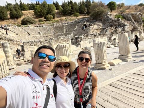       Three people with ancient ruins in the background.
  