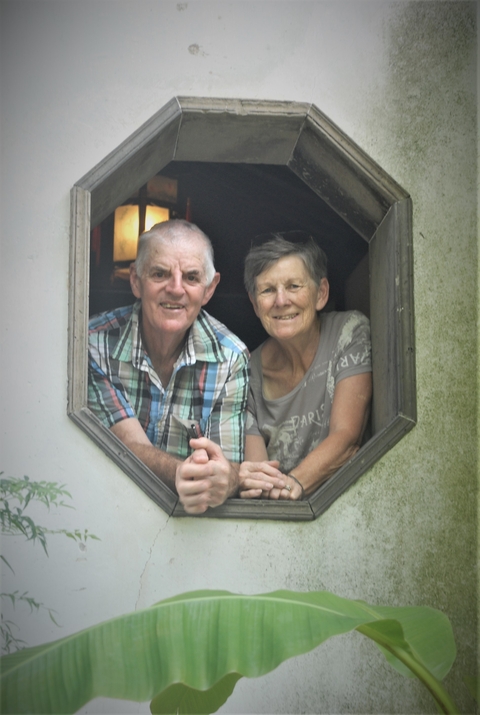 Two people smiling from an open window.