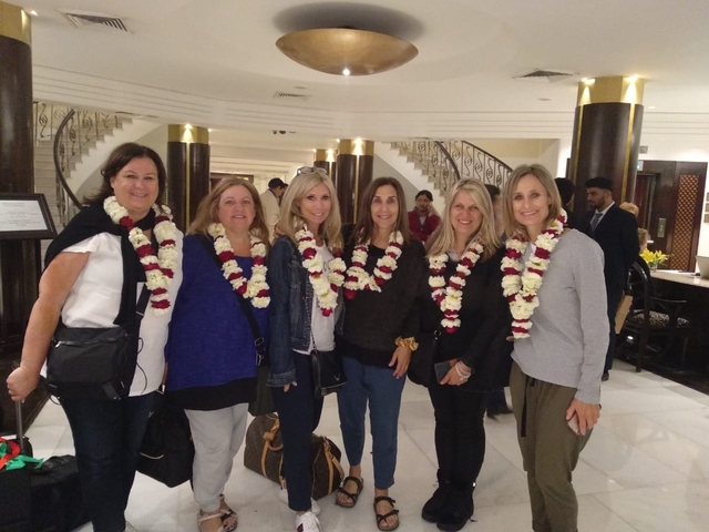 A group of women wearing garlands around their necks standing inside a building.