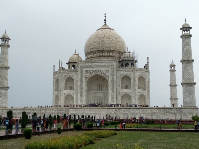 A frontal view of the Taj Mahal surrounded by gardens and tourists.