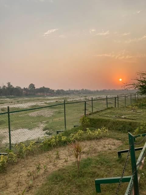 Sunset over a fenced-off grass field.