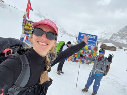 Upside-down selfie with a welcome sign at a snowy base camp.