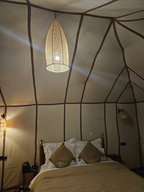 Interior view of a tent with bedding and a lamp.
