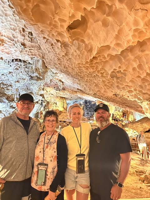 Visitors in a cave with stalactites and rock formations.
