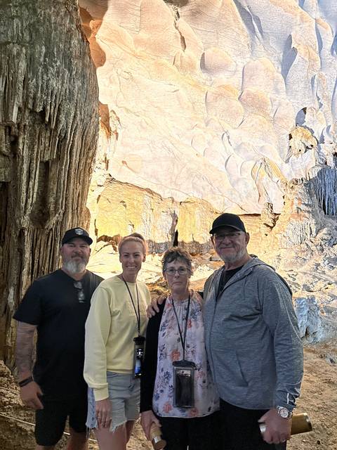       Visitors inside a cave with illuminated rock formations.
  