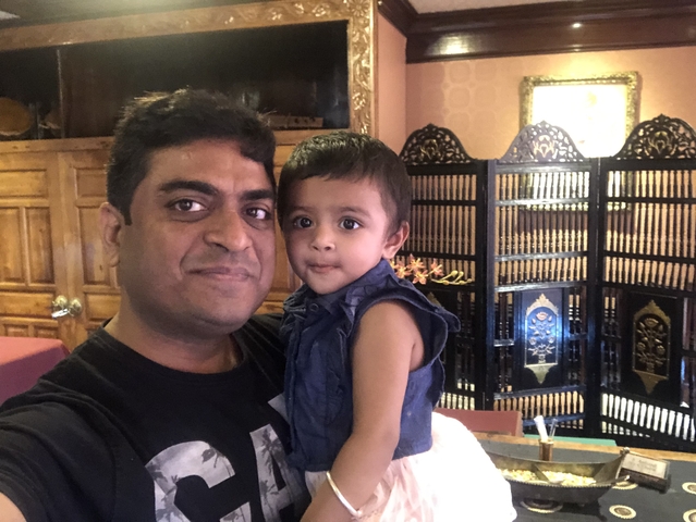       Man holding a child in an interior setting.
  