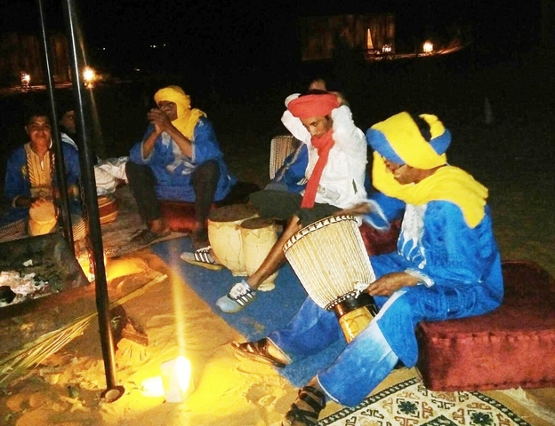       Group playing traditional instruments around a fire.
  