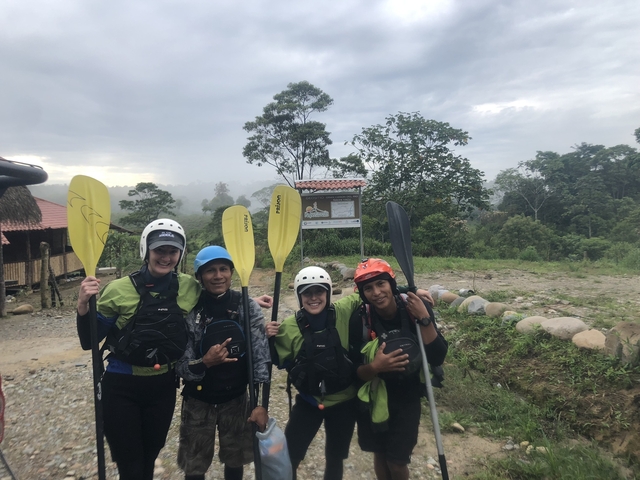       Group of people with paddles standing outdoors.
  