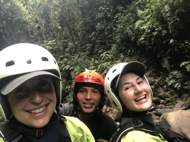       Three people wearing helmets in a lush, green environment.
  