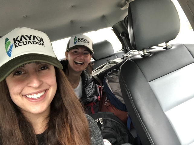       Two women smiling inside a vehicle with Ecuador hats.
  