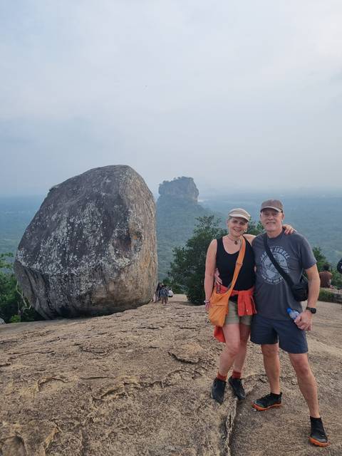Couple posing with a large rock and distant mountain.