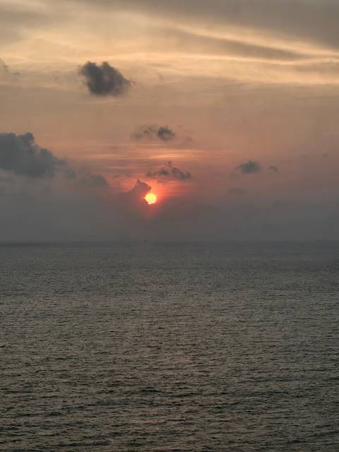 Sunset view over the ocean with clouds and sun rays.