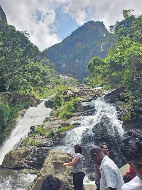 Tourists observing a waterfall cascading down rocks.