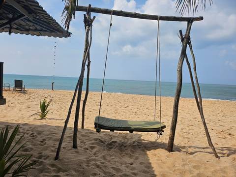 Sandy beach with swing set and blue ocean.