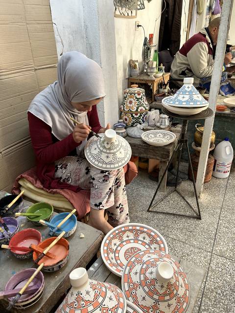       Woman painting traditional pottery designs.
  