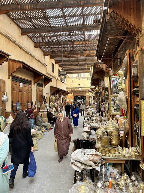       Crowded marketplace with people shopping and displaying merchandise.
  