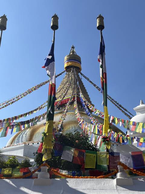       Colorful prayer flags at a stupa with a golden spire.
  