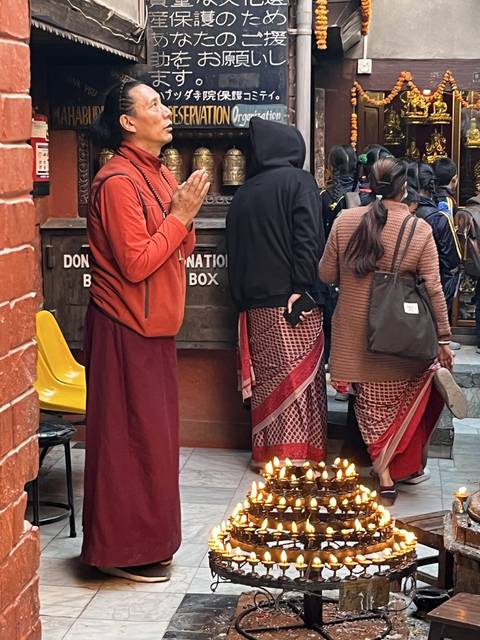       People praying and lighting candles in a temple.
  