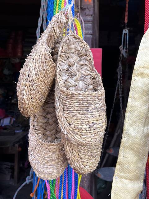 Woven straw slippers hanging for display.
