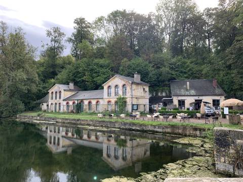 Building reflected in water, surrounded by forest.