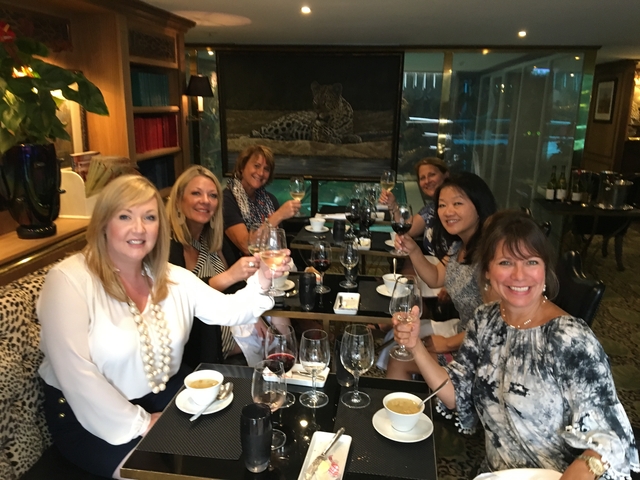 Group of women toasting with drinks in a cozy dining area.