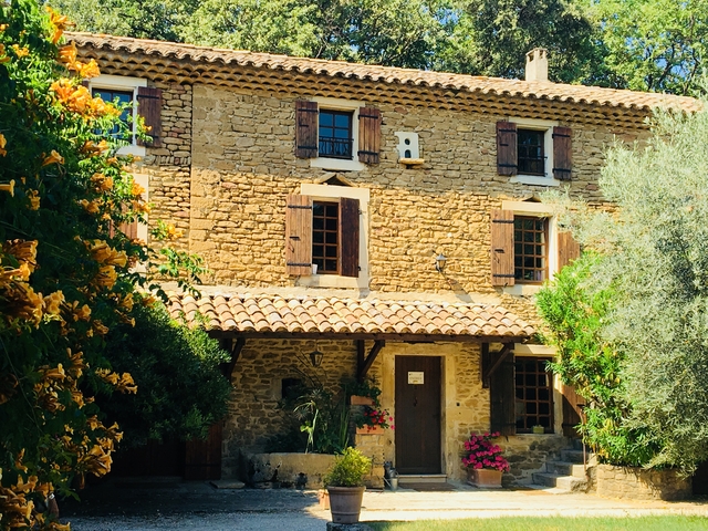 Stone house with flowers surrounding it.