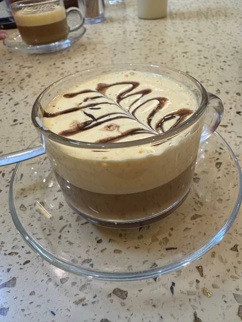 A dessert in a glass bowl with artistic chocolate drizzle.