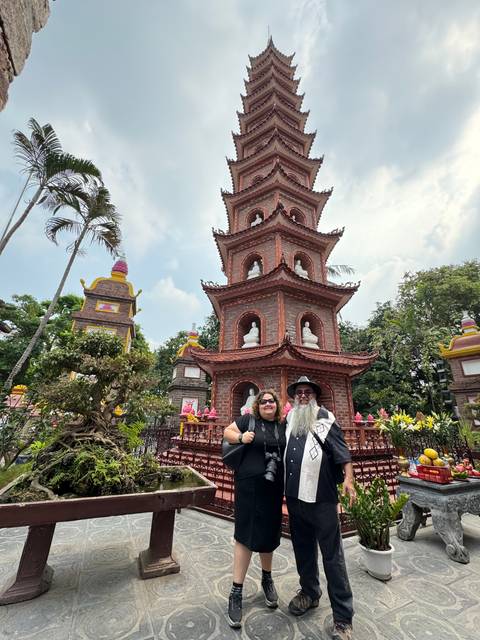 Two people posing in front of a pagoda structure.