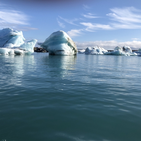 Icebergs floating in a serene lagoon with reflections on water.