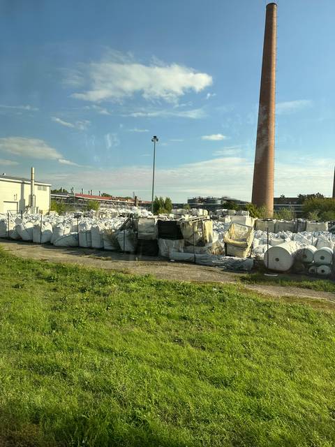       Industrial yard with chimney and stacked materials.
  