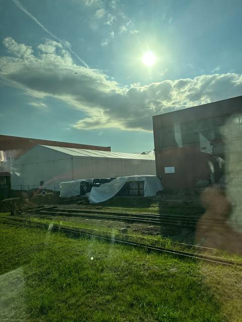       Tented structure in an industrial area with sun in the background.
  