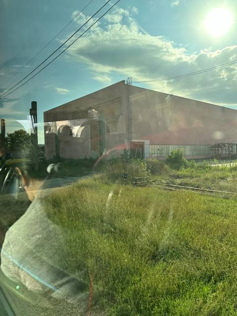 Large industrial building with grass and power lines.