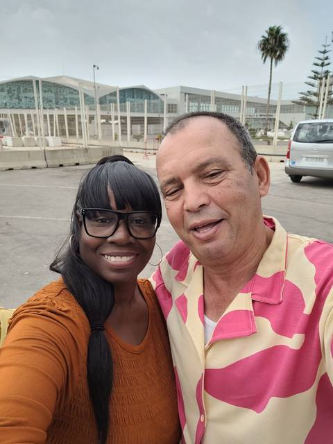 Selfie of two people near a modern building.