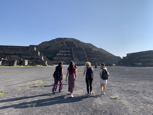 People walking towards a large ancient pyramid.