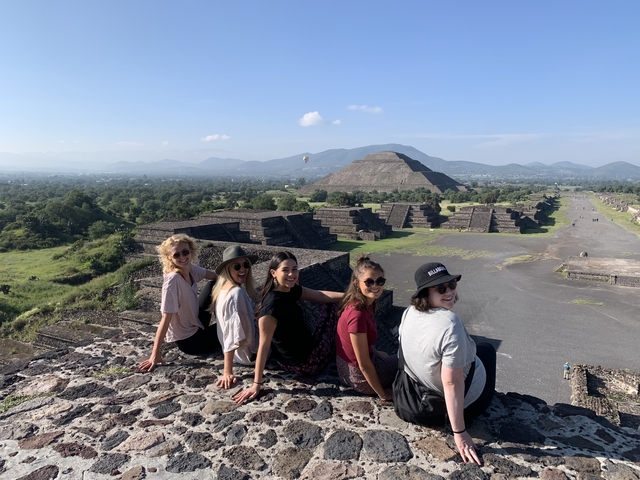 Group of people sitting on ancient pyramid steps.