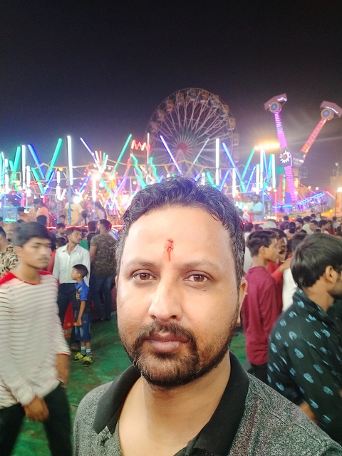       Crowded street fair with bright lights at night.
  