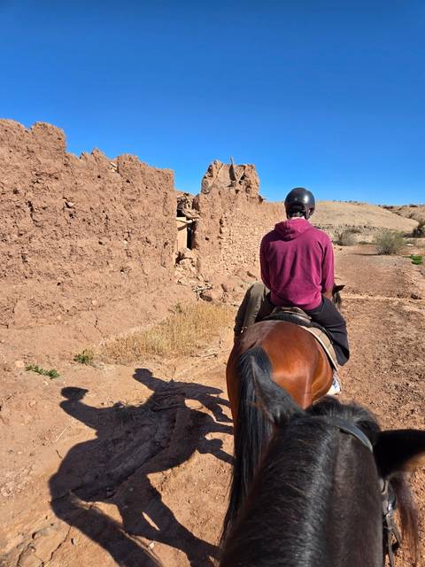 A person riding a horse near ancient ruins.