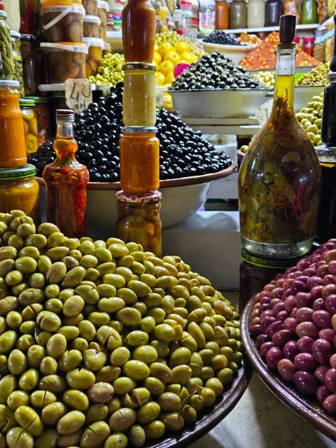       Colorful selection of olives and preserved food at a market.
  