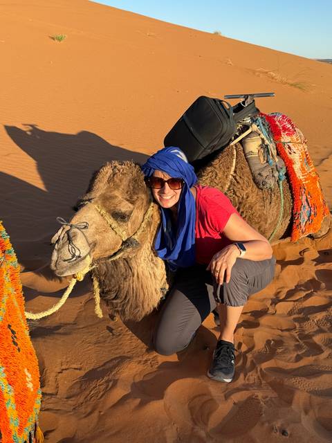       Person lying on a camel in the desert.
  