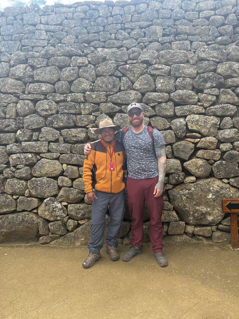 Two people standing in front of a stone wall.