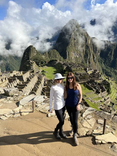       Two women posing at the ruins of Machu Picchu.
  