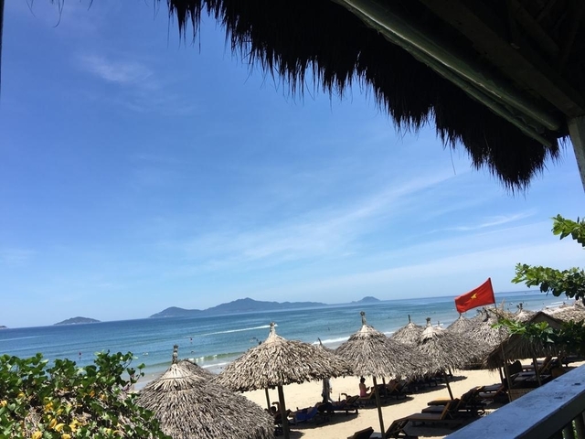 Beachfront view with mountains and a flag.