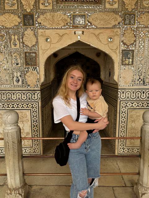       Person holding a child in an ornate historical building.
  