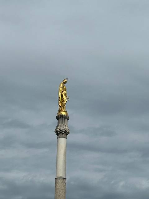       Golden statue on top of a tall column.
  