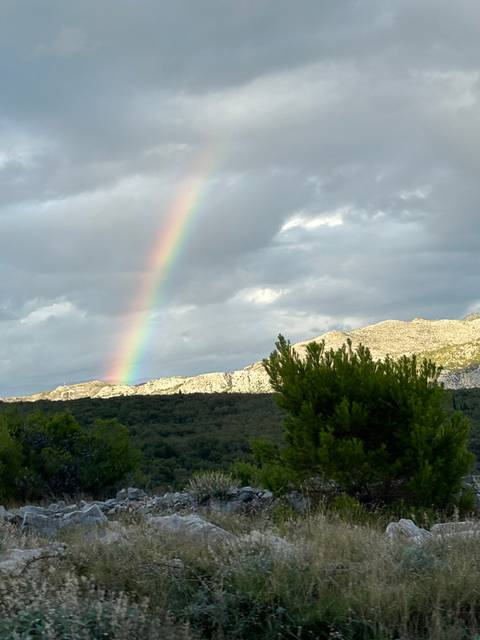       Scenic view with a rainbow and cloudy sky.
  
