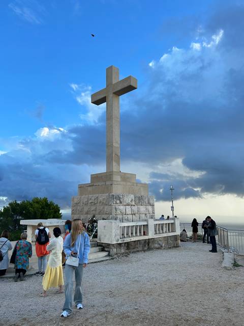       Cross monument with tourists visiting.
  