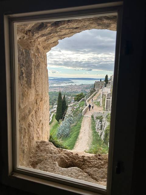       View through an archway overlooking a coastal city.
  