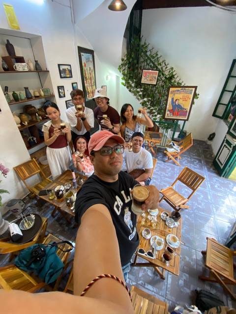 Group of people enjoying drinks at a cafe with a cozy interior.