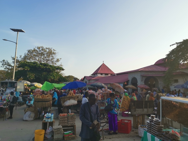       A busy market scene with people and stalls.
  